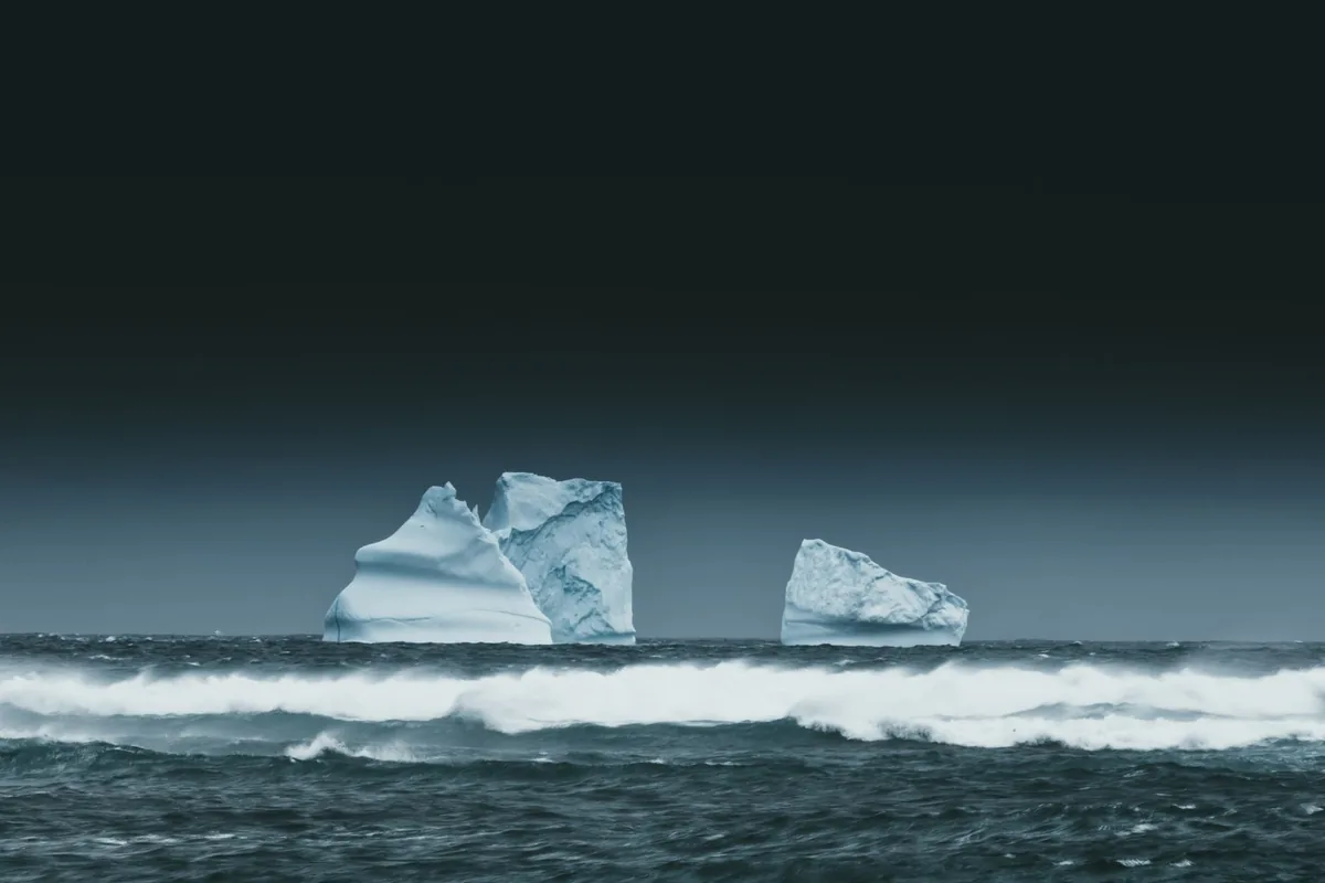 Majestic icebergs and crashing waves under a dark sky, symbolizing polar climate change.